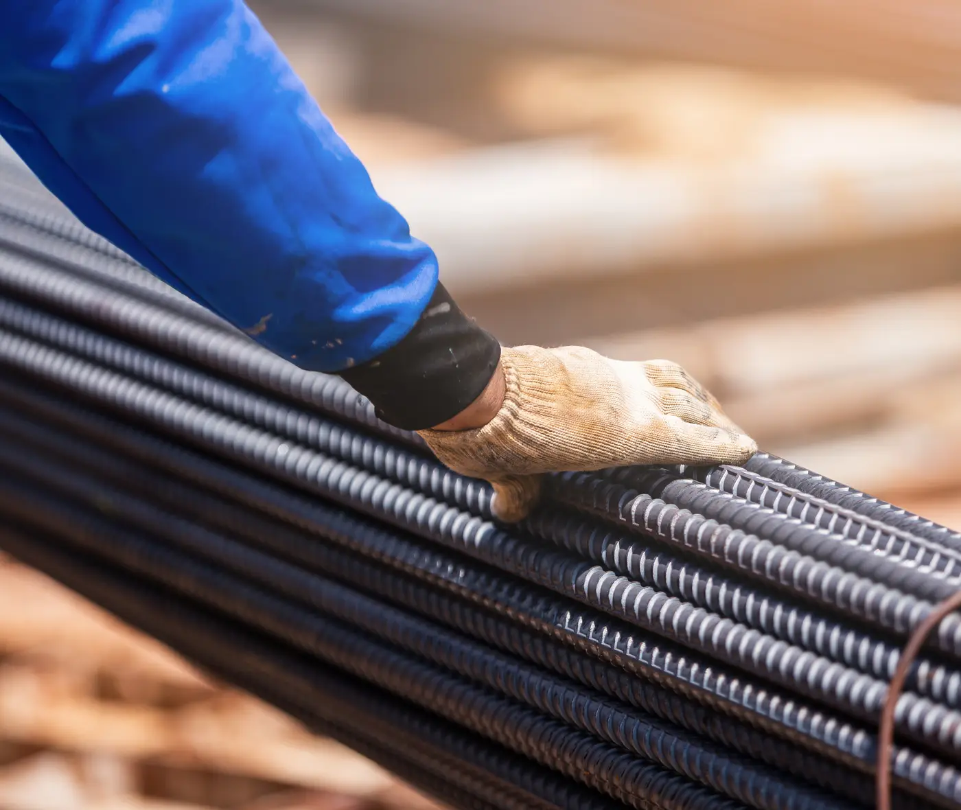A gloved hand resting on tied rebar before a pour