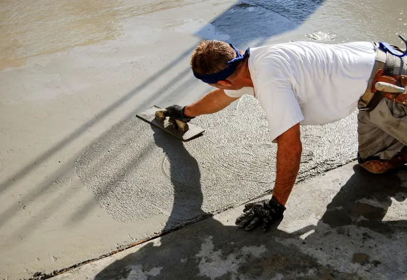 A mason smoothing fresh concrete on a new slab