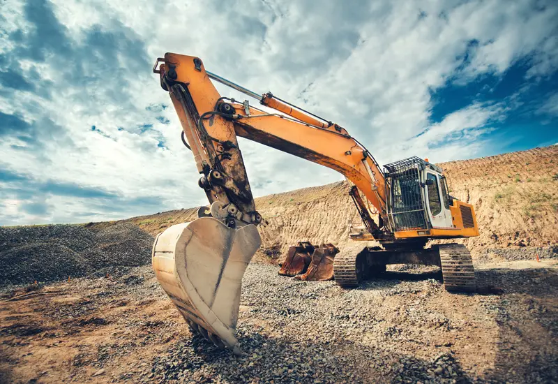 An excavator bucket raised against a dramatic sky