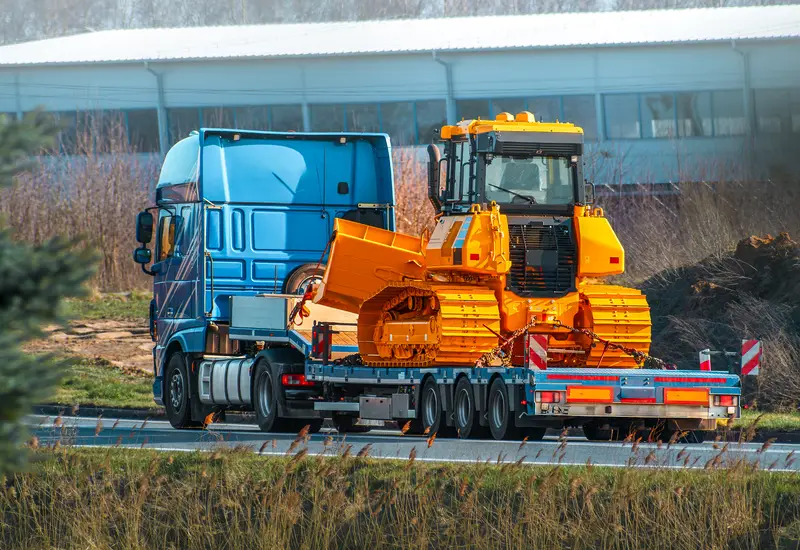 A Belco blue truck hauling a dozer to a jobsite