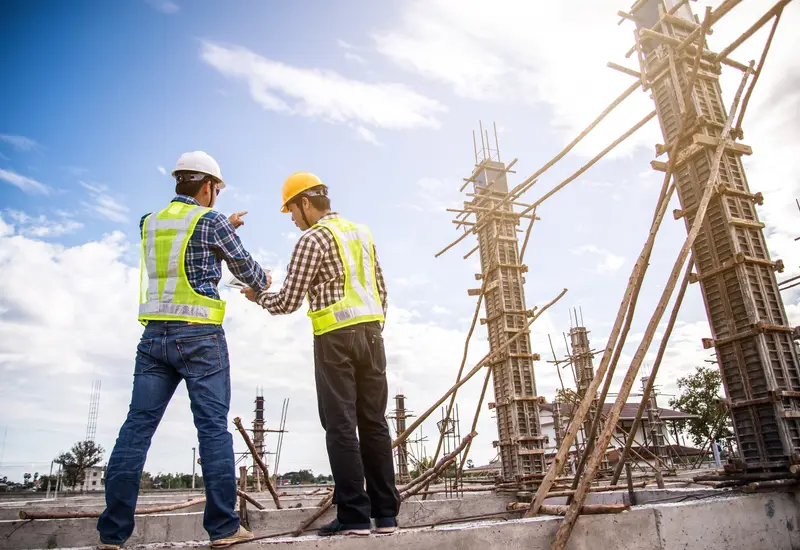 An engineer briefing a worker beside a trench on site